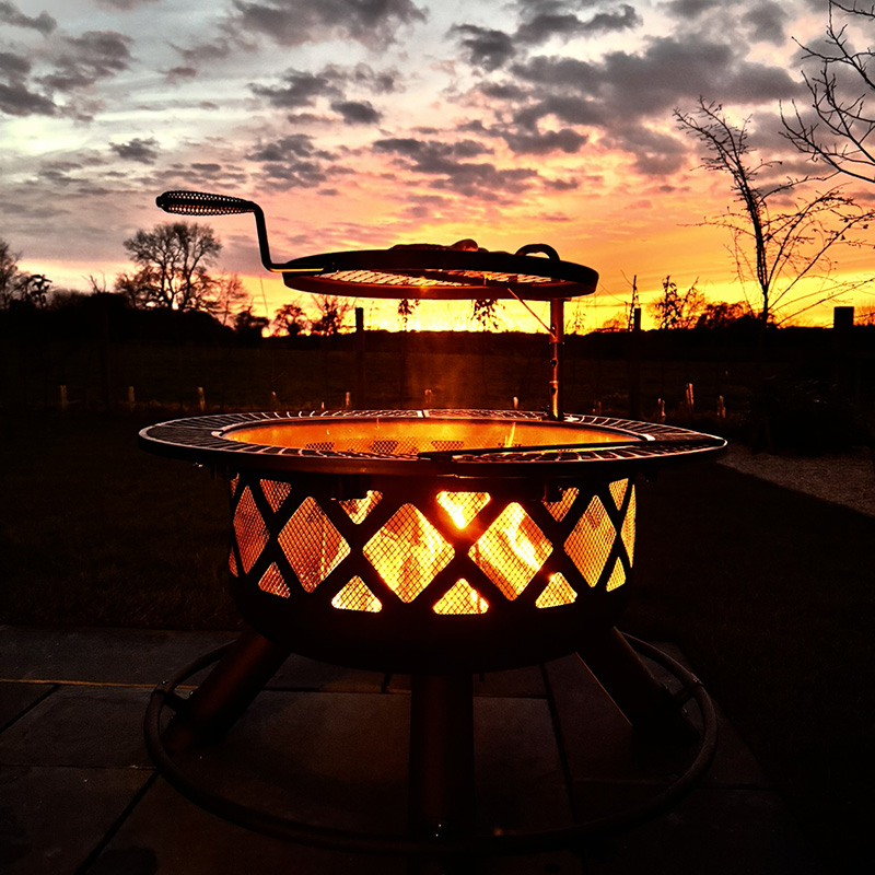 fire Image showing an outdoor fire pit and grill, with sunset in the background